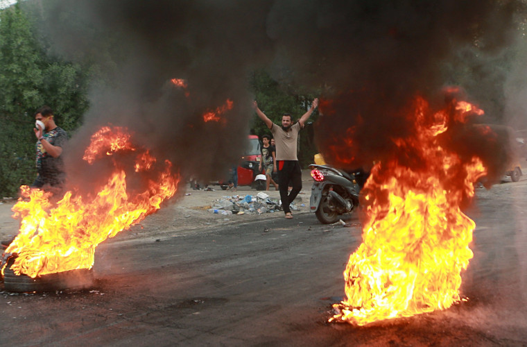 Image: Anti-government protesters set fires and close a street during a demonstration in Baghdad, Iraq