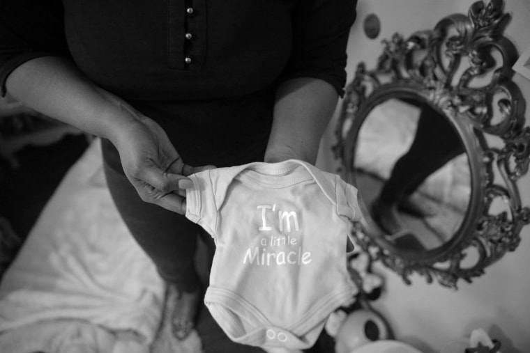 Ajshay James holds a onesie that was too big for her daughter when was born 16 weeks premature.