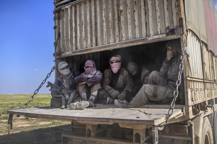 Image: A truck carrying men, identified as Islamic State group fighters who surrendered to Kurdish-led Syrian Democratic Forces (SDF), as they are transported out of IS's last holdout of Baghouz in Syria's northern Deir Ezzor province