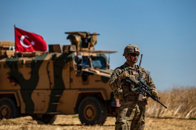 Image: A U.S. soldier stands guard during a joint patrol with Turkish troops in the Syrian village of al-Hashisha on the outskirts of Tal Abyad town along the border with Turkey