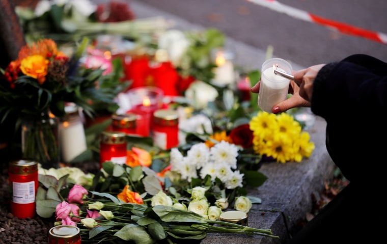 Image: A woman lights a candle at a makeshift memorial in Halle, Germany Oct 10, 2019, after two people were killed in a shooting.