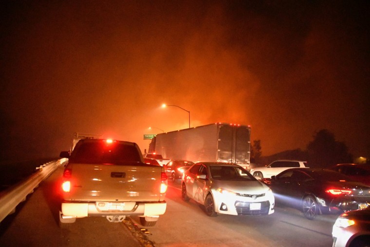 Image: Freeway traffic comes to a standstill as a wind-driven wildfire burns in Sylmar, CA