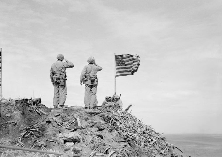 Moments after the second flag has been raised. Lt. Harold G. Schrier salutes on the left and Plat. Sgt. Ernest I. Thomas Jr. on the right.
