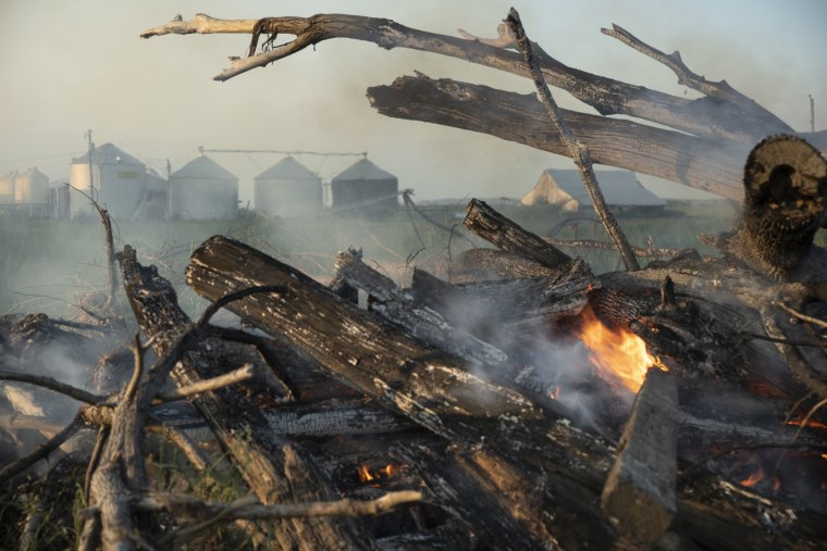 David Lieth burns driftwood that settled on his farmland after floodwaters overtook them earlier this year.