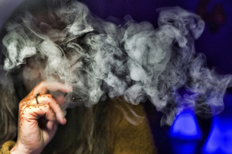 A woman takes a puff from a cannabis vape pen in Los Angeles