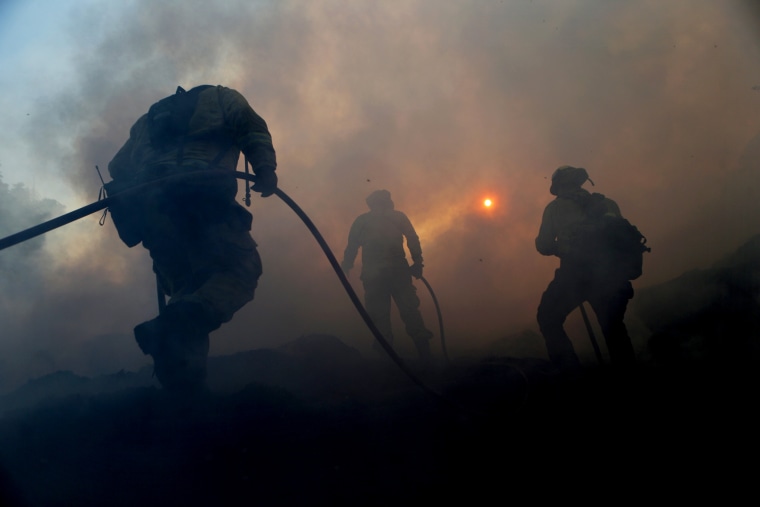 Image: Firefighters work to contain a flare up of the Saddleridge Fire at a mulch supplier in Sylmar, Calif., on Oct. 12, 2019.