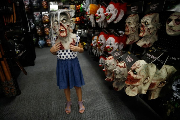 Image: Girl wears zombie mask at a Halloween store