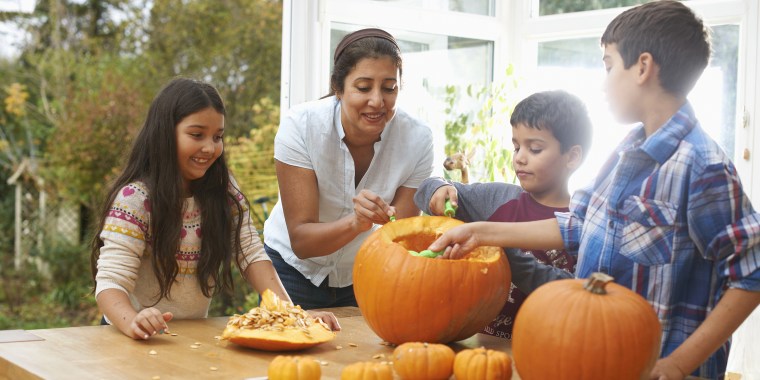 Mother and children carving pumpkin in dining room