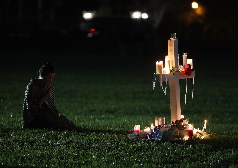 Former Douglas student, Rachelle Borges, sits near a candlelit cross during a vigil.