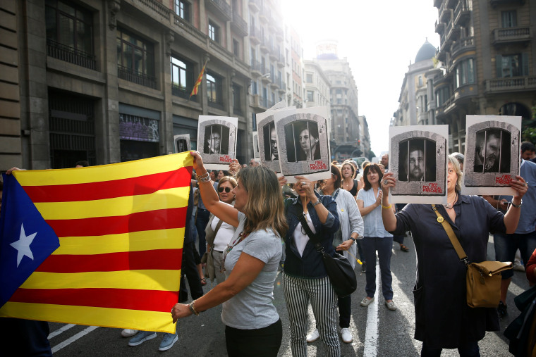 People holding an Estelada and pictures of Catalan politicians as they walk through Via Laetana Avenue during a protest after a verdict in a trial over a banned independence referendum, in Barcelona