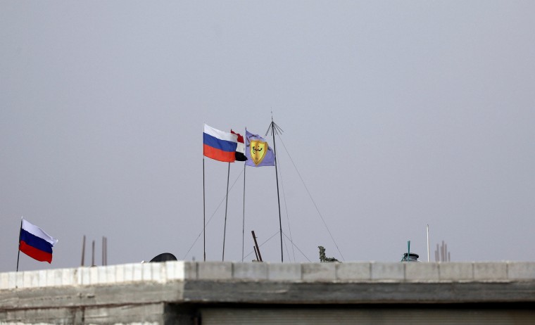 Image: Russian, Syrian and Manbij military council flags flutter near Manbij, Syria