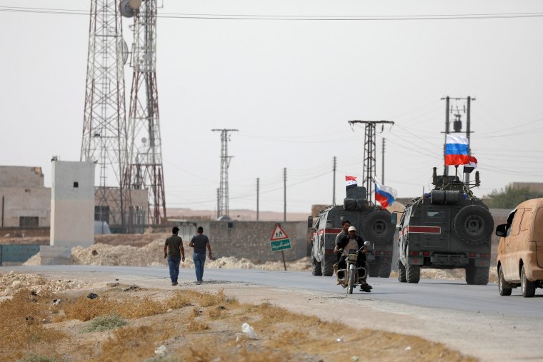 Image: Russian and Syrian national flags flutter on military vehicles near Manbij