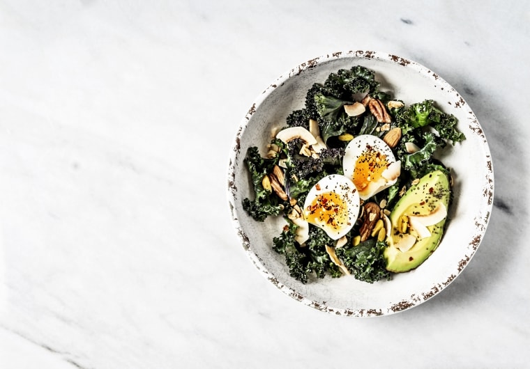 Image: Bowl of kale salad with boiled eggs and avocado on white background