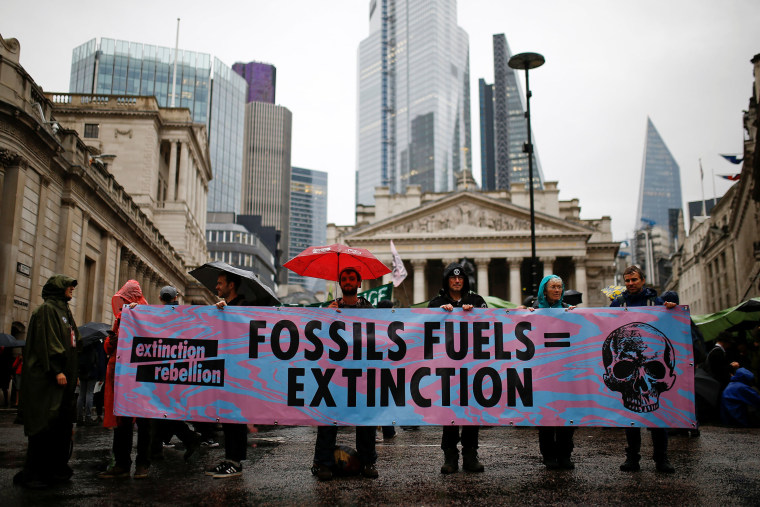 Image: Protesters hold a banner as they block the road during an Extinction Rebellion demonstration at Bank, in the City of London