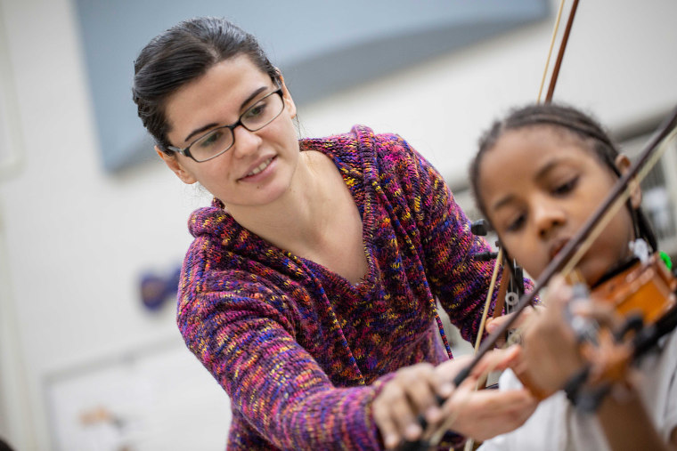 A Detroit Public Schools Community District (DPSCD) teacher provides instruction to a student about bow placement on a violin at Spain Elementary-Middle School. 