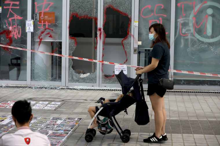 Image: A woman with a stroller stands in front of the smashed glass door of the Hong Kong Design Institute during a demonstration in Tiu Keng Leng in Hong Kong, China