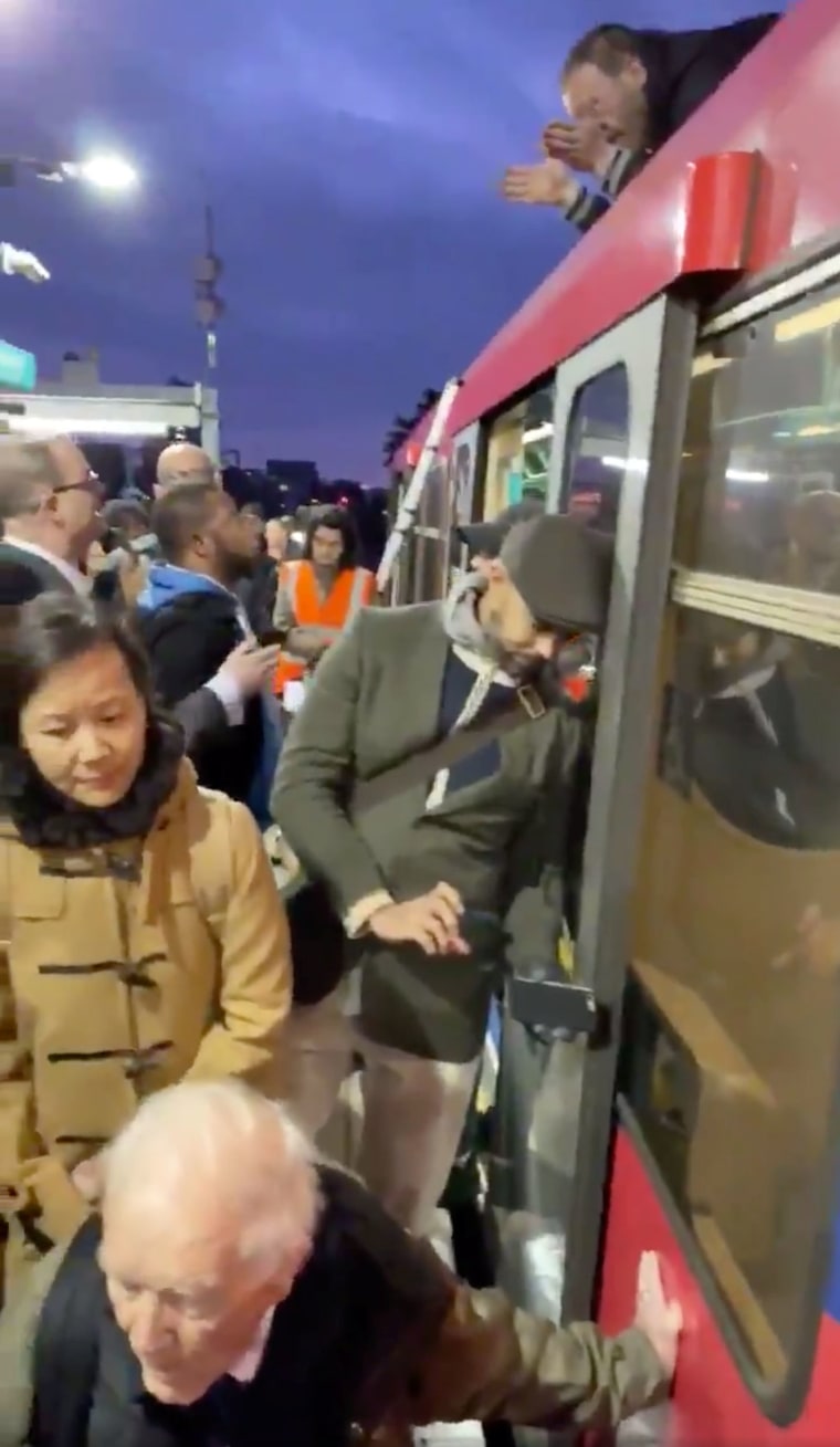 Image: People look at Extinction Rebellion protesters glued onto the train at the Shadwell DLR station in London