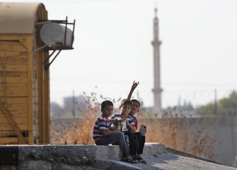 Image: Children gesture to the camera in Akcakale Sanliurfa province, southeastern Turkey, at the border with Syria