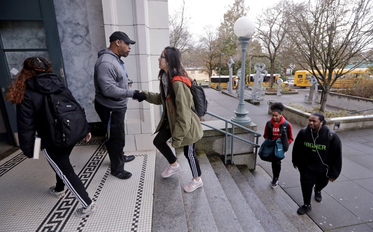 A teaching assistant greets students arriving at Franklin High School in Seattle in December 2018. In 2016, the district pushed back start times for high schools and most middle schools. 