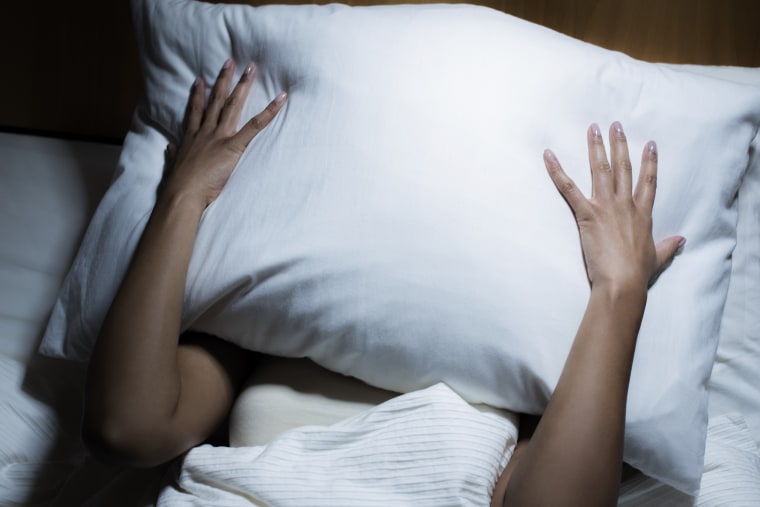 Woman covering her face with pillow