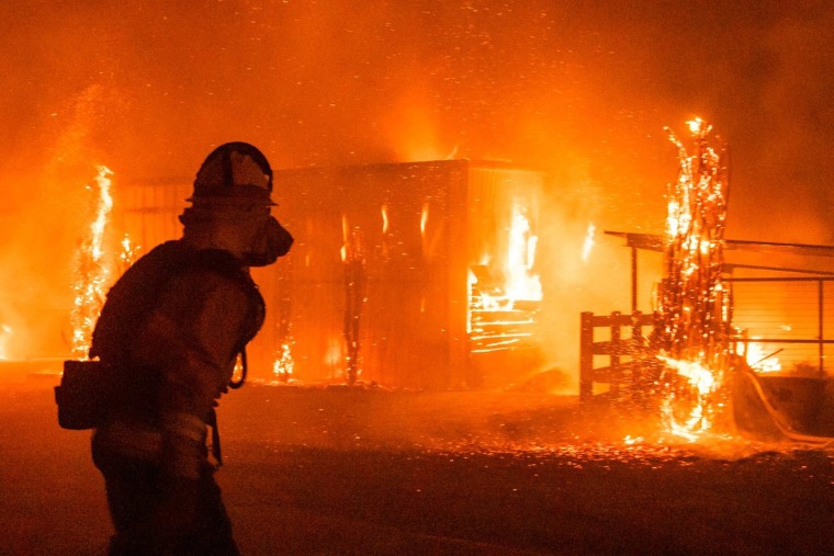 Image: Firefighters battle a wind-driven fire burning structures on a farm during the Kincade fire in Windsor, California.