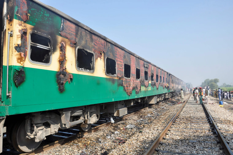 Image: Burnt-out train carriages sit on the rails after a passenger train caught on fire in Punjab 