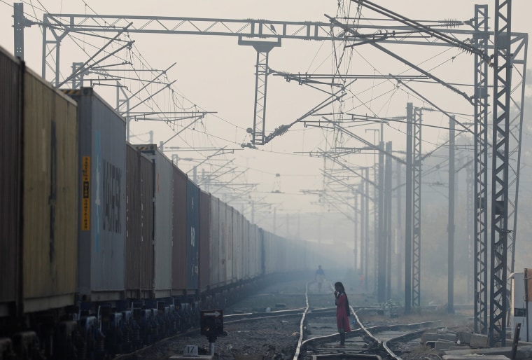 Image: A girl waits to cross the railway line on a smoggy morning in New Delhi