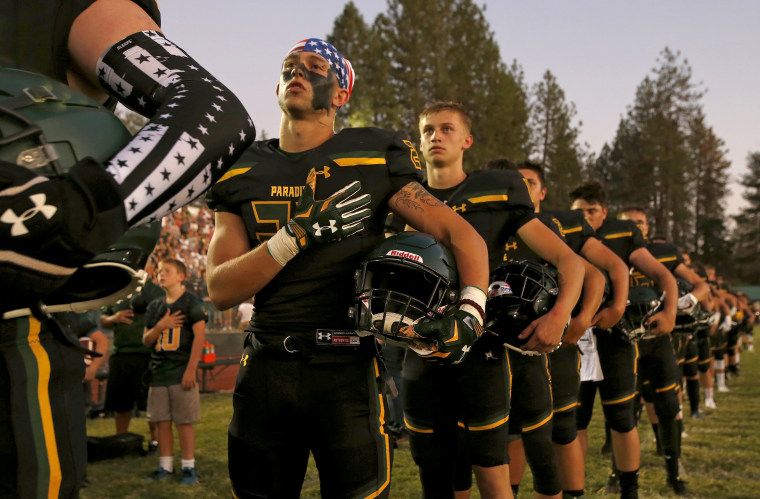 Members of the Paradise High School football team stand for the playing of the national anthem before their game against Williams High School in Paradise, Calif. on Aug. 23, 2019.