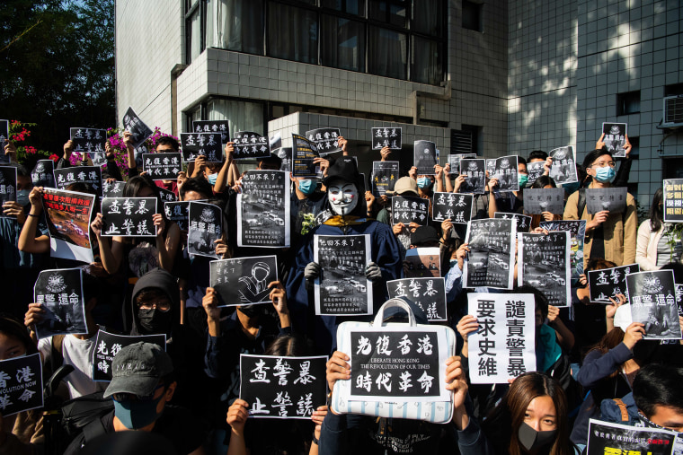 Image: Protesters hold a photos of Chow Tsz-Lok during a memorial flash mob to remember him in Hong Kong