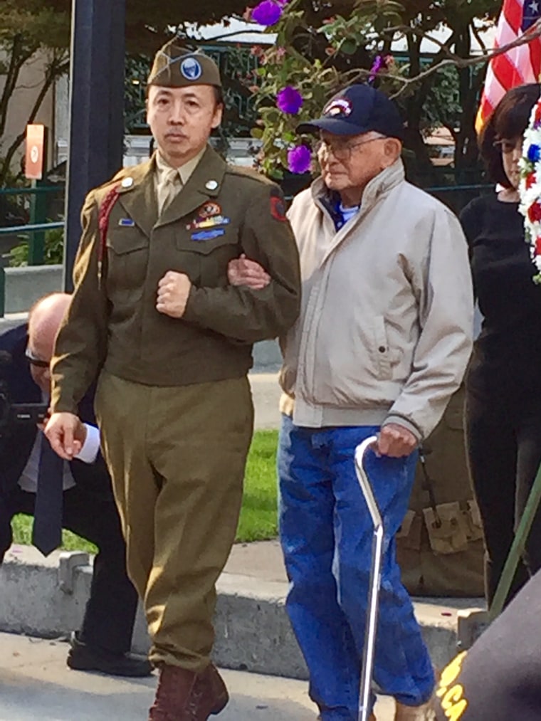 Randall Ching is escorted by Chris Fuchs to lay a wreath at the Chinese American World War I and World War II memorial at Saint Mary's Square Park in the Chinatown neighborhood of San Francisco.