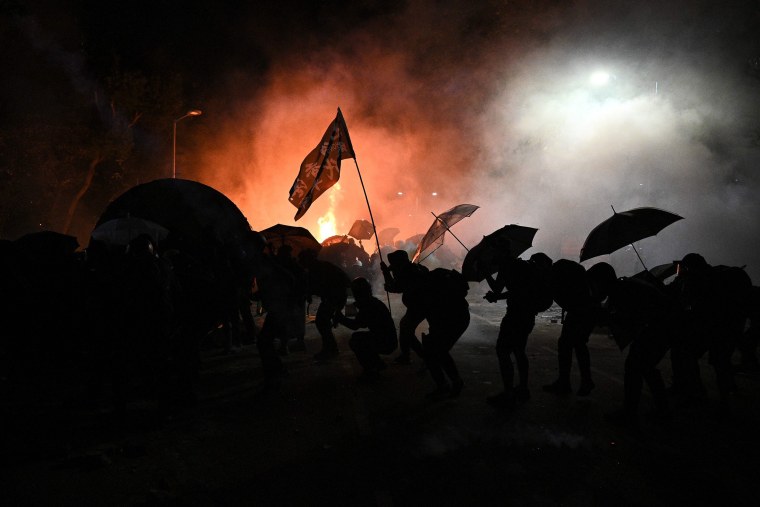 Image: Protesters take cover during clashes with police at the Chinese University of Hong Kong (CUHK), in Hong Kong