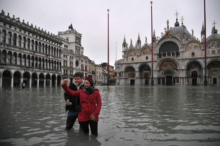 Image: People take selfies in flooded St. Mark's Square by St. Mark's Basilica 