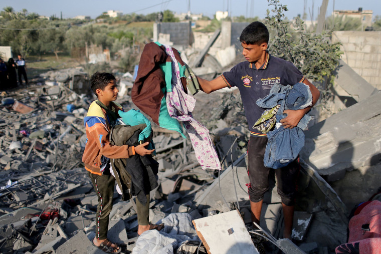 Image: Palestinians collect belongings from a house destroyed in an Israeli air strike in the southern Gaza Strip 