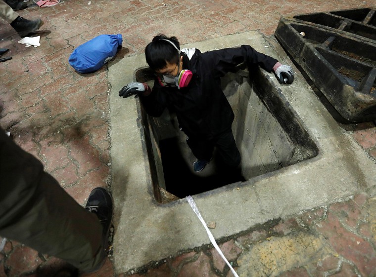 Image: A protester tries to escape through a sewage tunnel inside the Hong Kong Polytechnic University campus during protests in Hong Kong, China