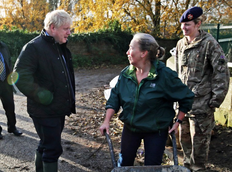 Image: Prime Minister Boris Johnson talks with a local woman pushing a wheelbarrow during a visit to Stainforth to see the recent flooding