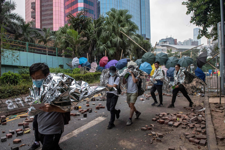 Image: Protesters are escorted out of the main entrance to Hong Kong Polytechnic University campus in the Hung Hom district in Hong Kong