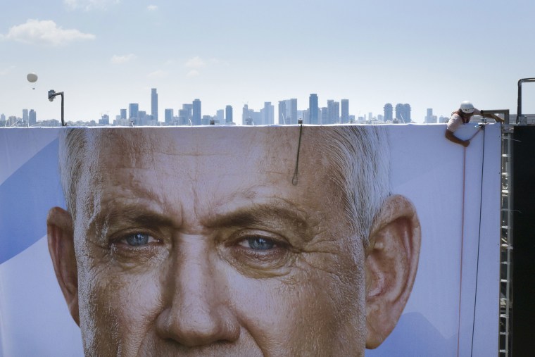 Image: A worker hangs a massive election campaign billboard that shows the Blue and White party leader Benny Gantz, in Tel Aviv,