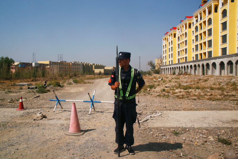 A Chinese police officer takes his position by the road near what is officially called a vocational education centre in Yining