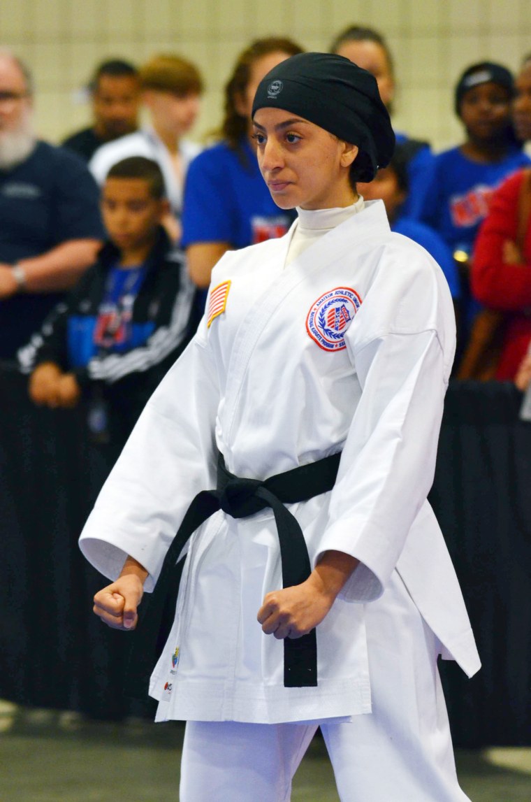 In competitions, Aprar Hassan wears an athletic cap and a white turtleneck underneath her robe.