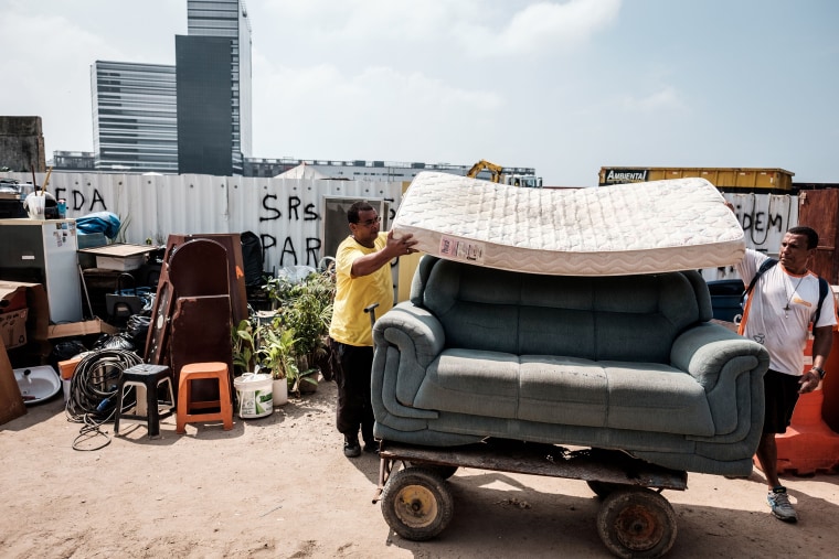 People help a resident move her belongings after her house was demolished