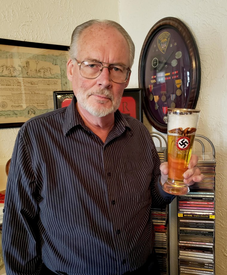 Image: James Mason holds a beer glass emblazoned with a swastika.