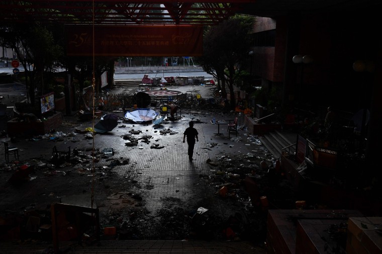 Image: A man walks past debris littering the entrance at the Hong Kong Polytechnic University campus in the Hung Hom district of Hong Kong