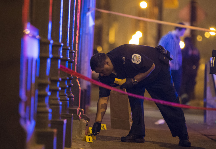 A Chicago police officer collects evidence at a crime scene where a man was shot in Chicago