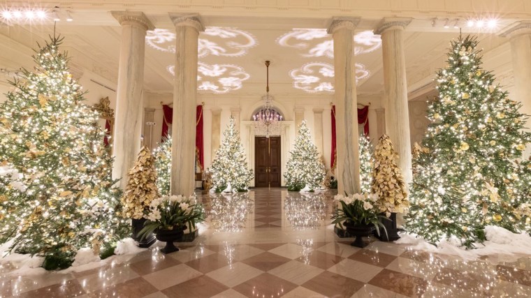 The Grand Foyer is lit up in gold as faux snow dusts the floor and trees.