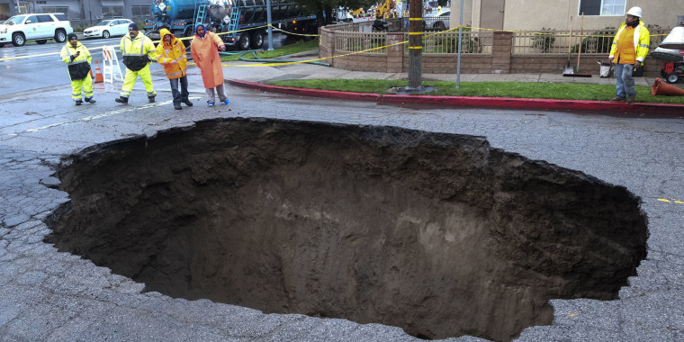 Inspectors examine a sinkhole in Studio City, north of Los Angeles, on Feb. 18, 2017. Two vehicles fell into the 20-foot sinkhole and firefighters had to rescue Stephanie Scott who escaped her car but was found standing on her overturned vehicle.