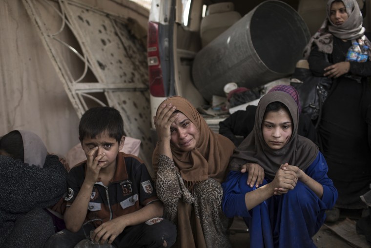 Image: Fleeing Iraqi civilians sit inside a house as they wait to be taken out of the Old City