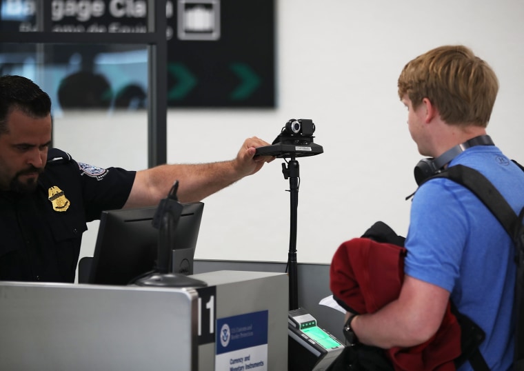 A U.S. Customs and Border Protection officer instructs an international traveler to look into a camera as he uses facial recognition technology to screen a traveler entering the United States at Miami International Airport in 2018.