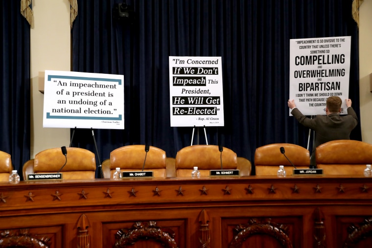 Image: A congressional staffer puts up signs before a House Judiciary Committee hearing on impeachment on Dec. 4, 2019.