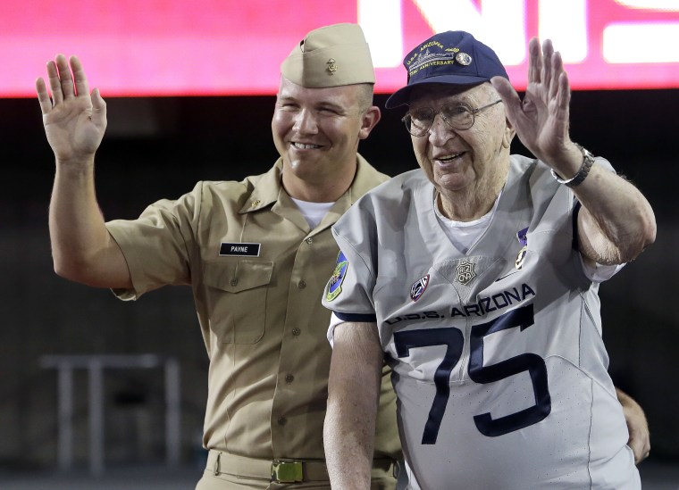 In this Sept. 17, 2016, photo, Pearl Harbor survivor Lauren Bruner, right, stands with Naval officer Scott Payne while honoring Pearl harbor during halftime of an NCAA college football game between Arizona and Hawaii in Tucson, Ariz.