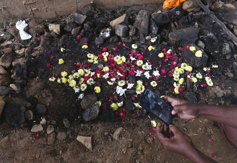 Image: A man takes photos of the site where the burned body of a 27-year-old woman was found last week by a passer-by in Shadnagar.